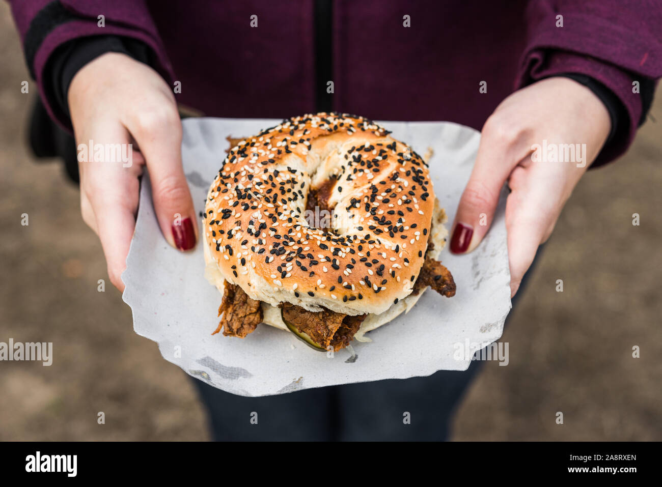 Bagel with pastrami beef meat and pickles at a street food market Stock