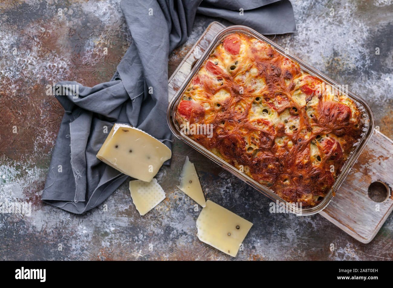 Cheese baked pie with olives in a glass baking dish on a rusty