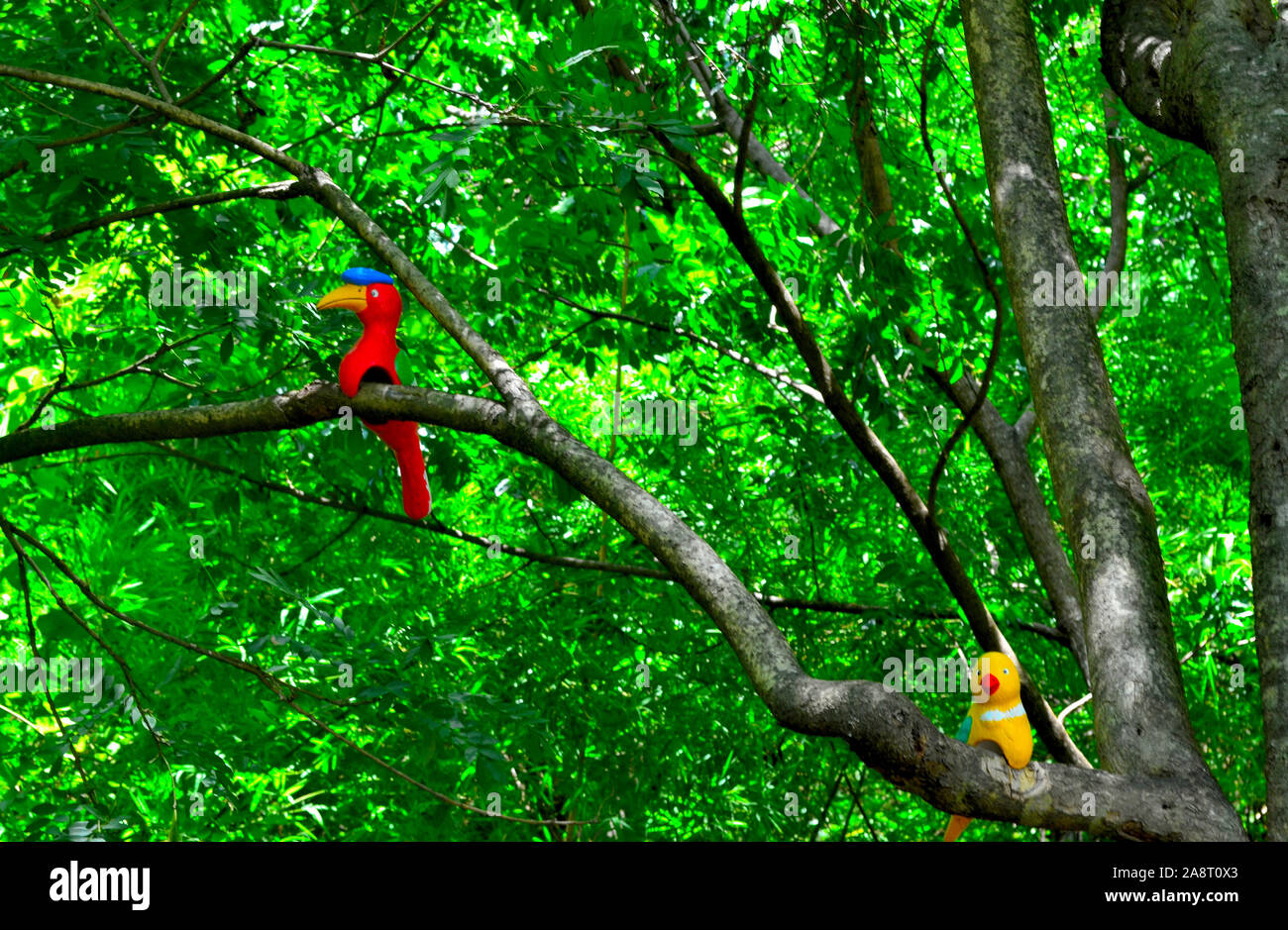 A red and blue bird statue perched in a tree at Wat Tham Khao Noi in Kanchanaburi Thailand Asia Stock Photo