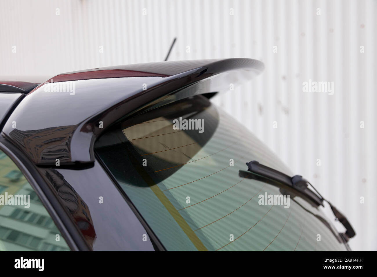 View of the trunk lid of a black car with a plastic spoiler over the rear window to improve the aerodynamics of the vehicle body during tuning for rac Stock Photo