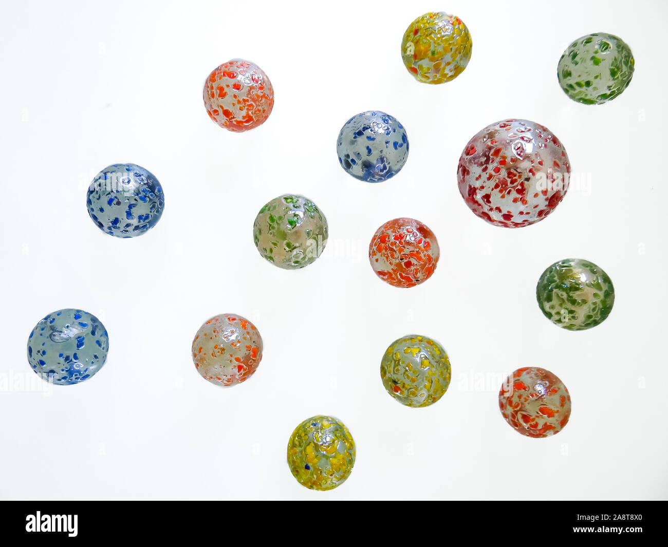 A big green glass marble between yellow, green, blue and red marbles on a  table Stock Photo - Alamy