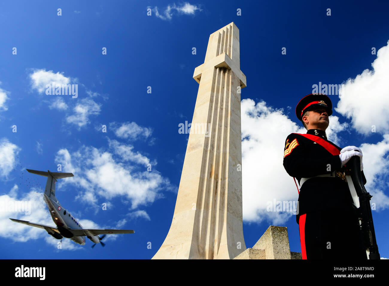 Beijing, Malta. 10th Nov, 2019. A soldier stands guard in front of the War Memorial as a military aircraft flies over in Floriana, Malta, on Nov. 10, 2019. Malta marked Remembrance Day to salute the war dead on Sunday. Credit: Jonathan Borg/Xinhua/Alamy Live News Stock Photo