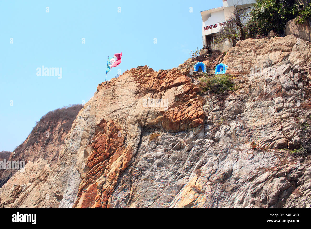 Mexican flag and altars of the Virgin Mary on top of famous diving cliff La Quebrada, Acapulco, Mexico Stock Photo