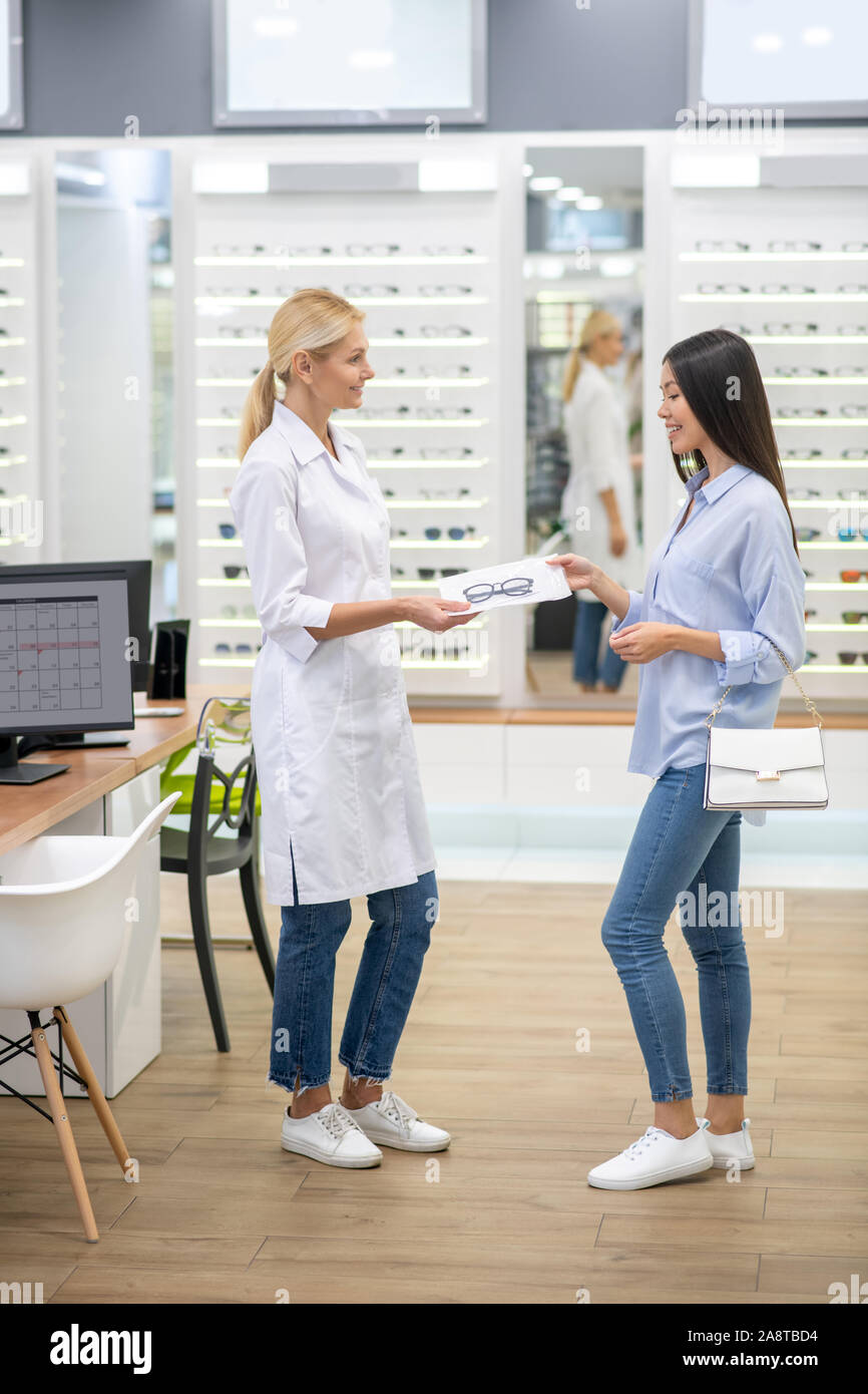 Blonde eye specialist giving new glasses to the customer Stock Photo