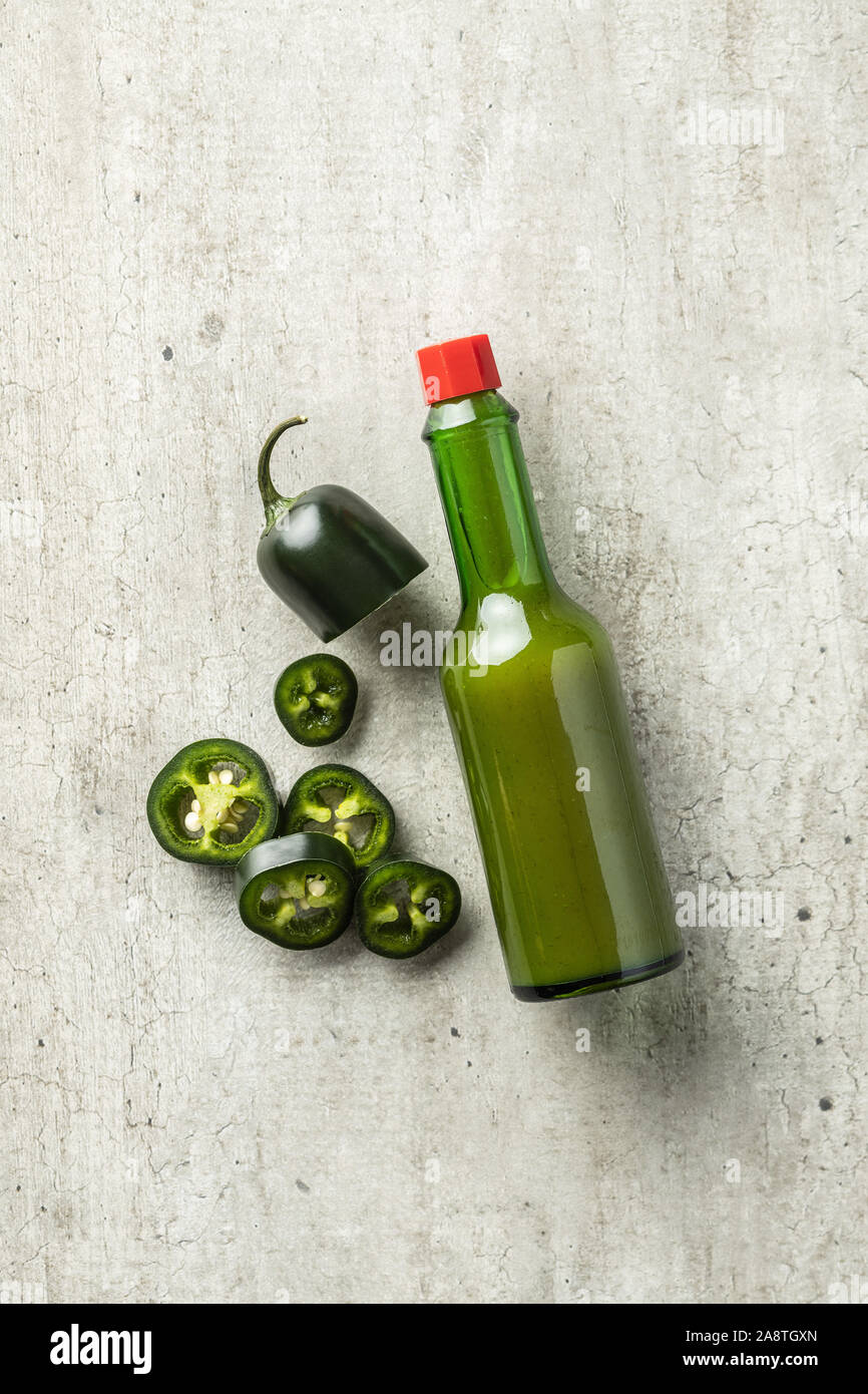 Sliced green jalapeno pepper and tabasco sauce. Top view. Stock Photo