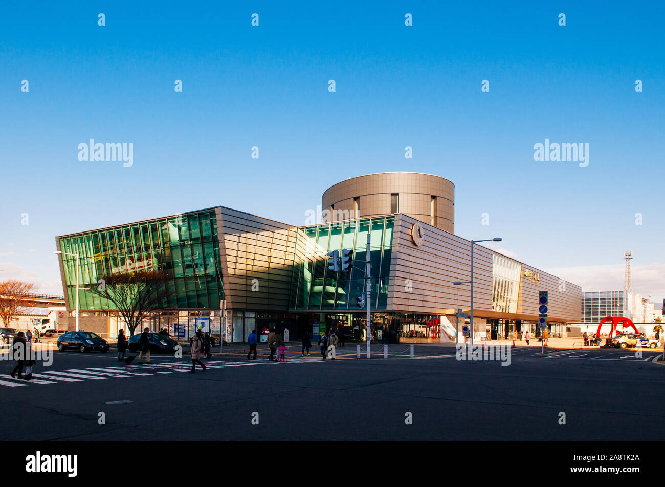 DEC 2, 2018 Hakodate, JAPAN - JR JR Hakodate Station building under bright sunlight in winter with tourists crossing road at junction. Stock Photo