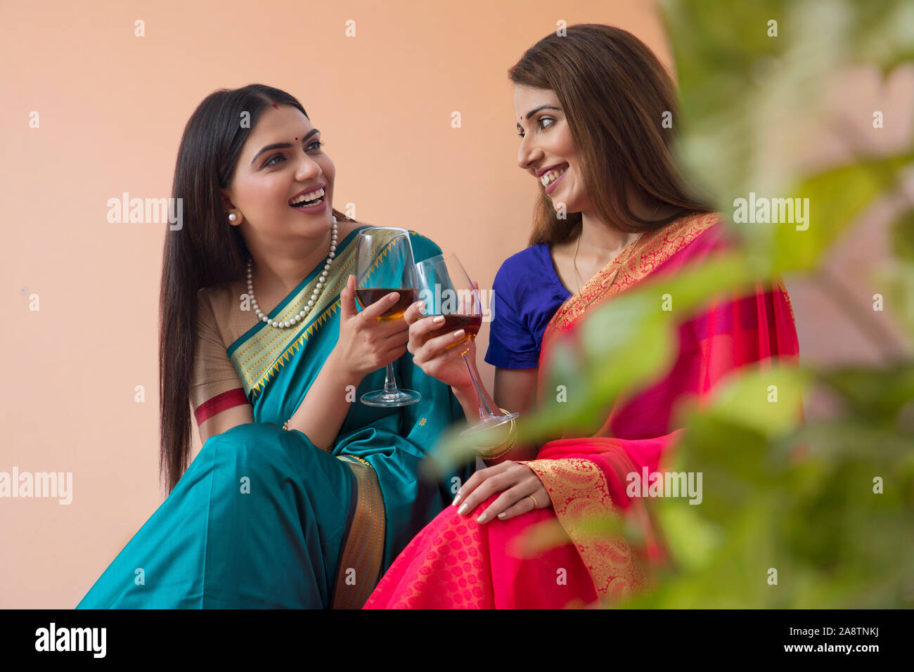 women in saree having a drink together Stock Photo