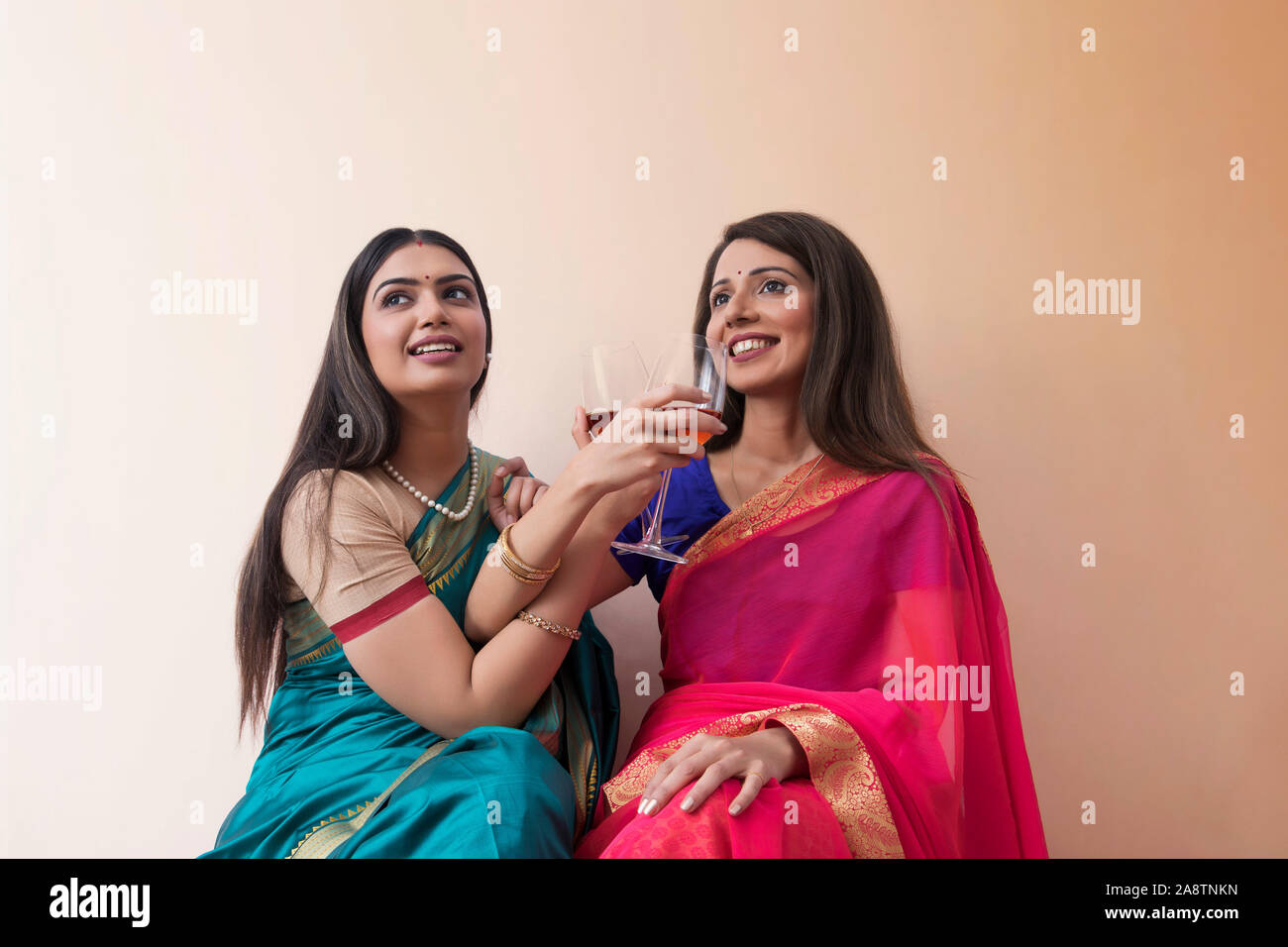 women in saree having a drink together Stock Photo