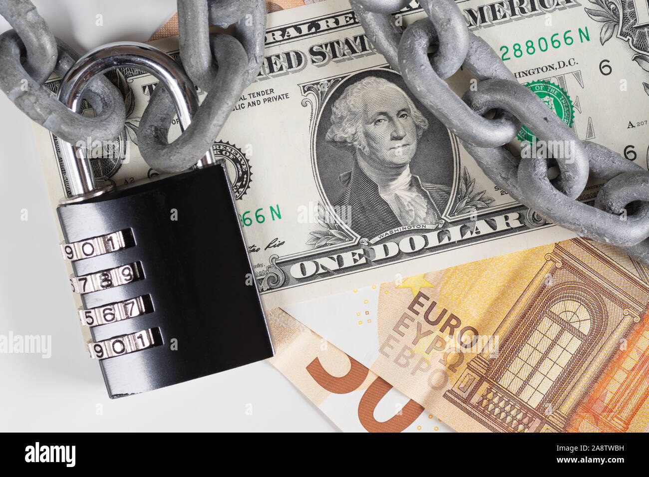 Closeup of US Dollar and European Union Euro banknotes under metallic chain and black combination padlock. Financial safety, currencies, protectionism Stock Photo