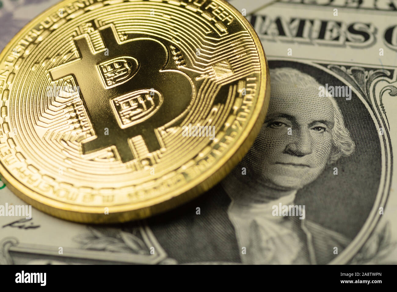 Golden Bitcoin cryptocurrency coin covering the image of George Washington on one US Dollar banknote Stock Photo