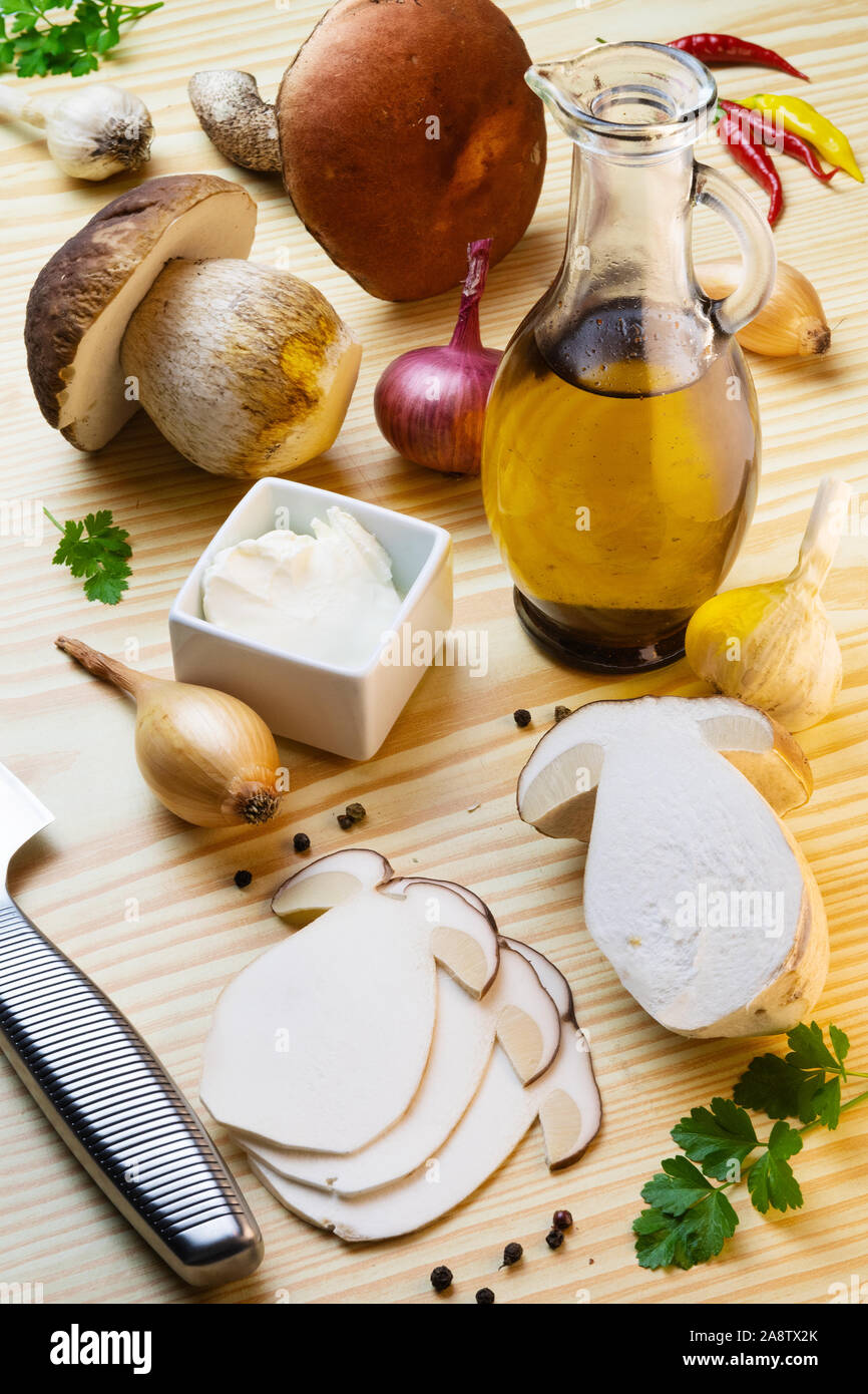 Sliced penny bun for mushroom carpaccio on table laden with spices, olive oil, garlic, onions and mushrooms. Cep, porcino, boletus edulis Stock Photo