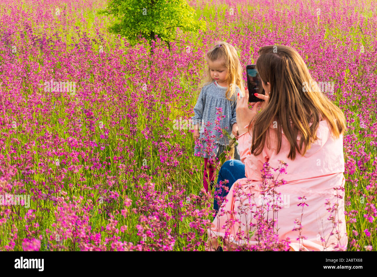 Mother woman making photos of her daughter girl using smartphone Stock Photo