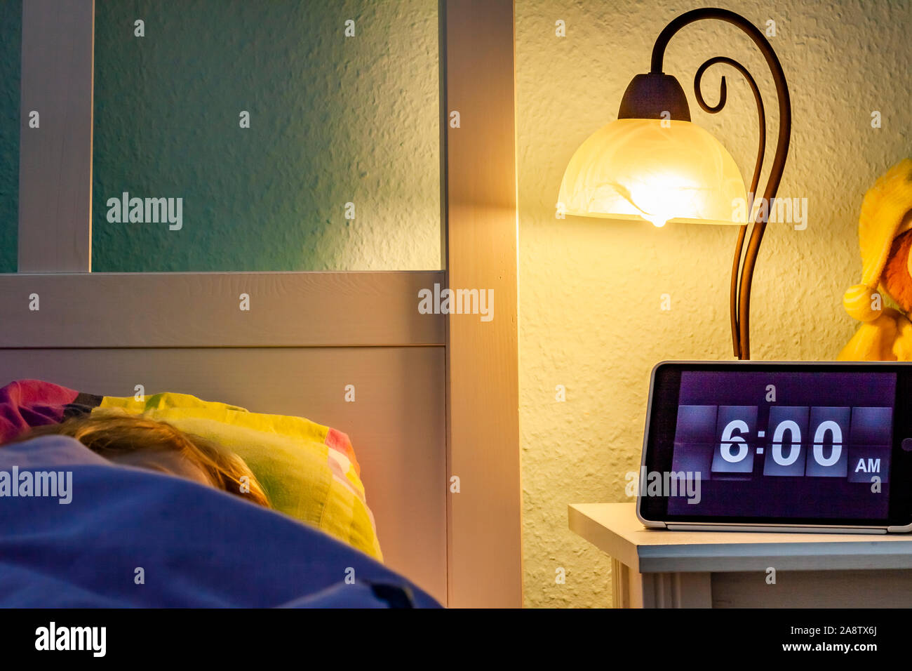 Little girl sleeping in bed Alarm clock at 6 am in the morning Stock