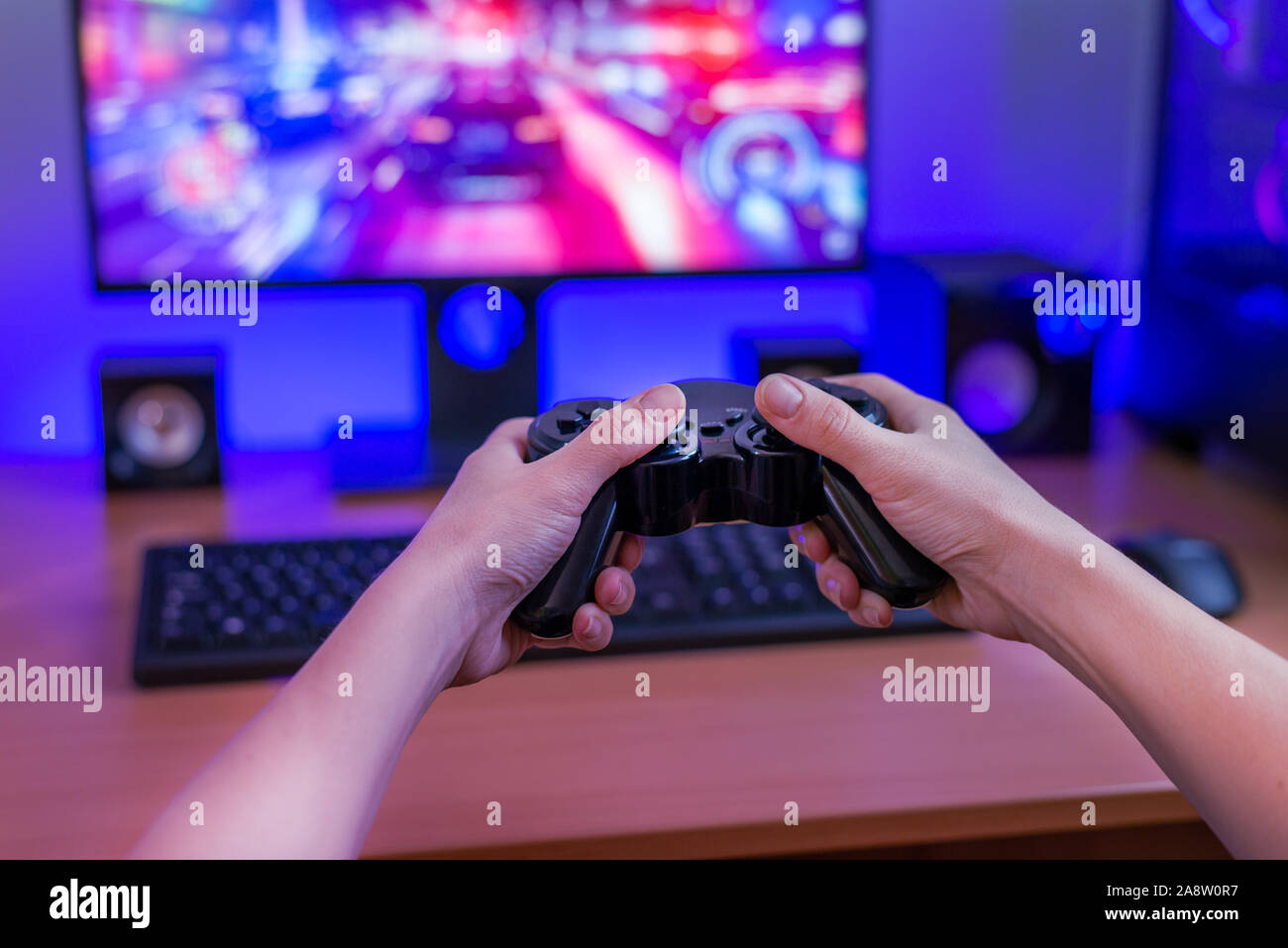 Gaming on a computer with a joypad. Game concept on computer display with RGB light. View from first person. Stock Photo