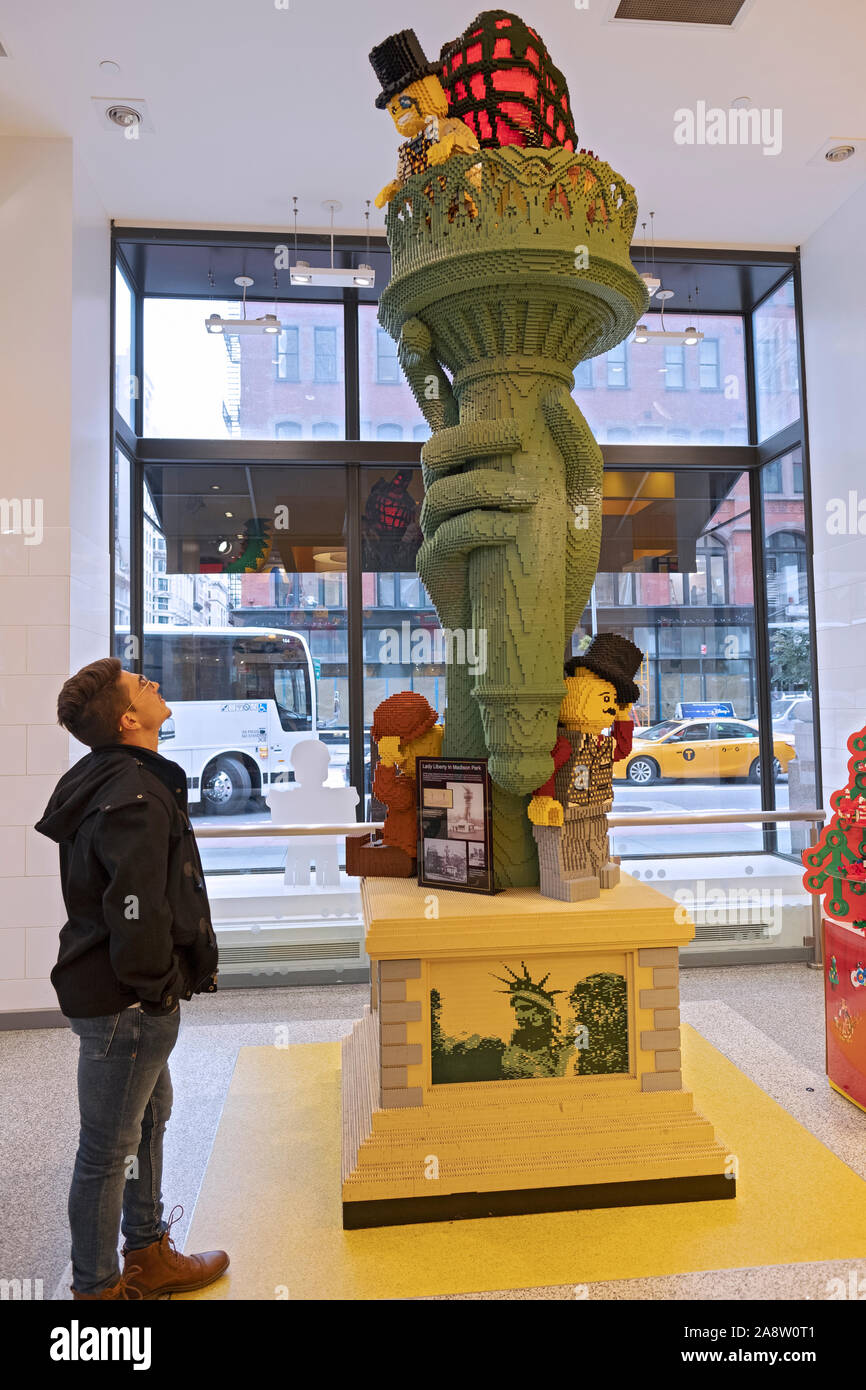 A tourist in the Lego Store on Fifth Ave admires a Lego sculpture of the Statue of Liberty's torch that was made out of more than 100,00 pieces. Stock Photo