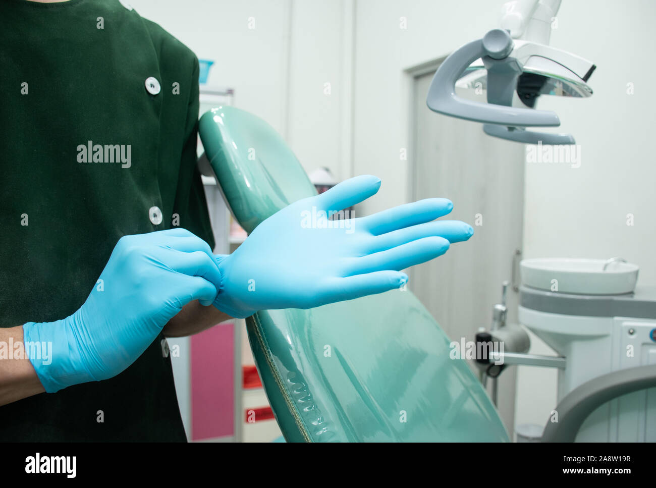 Male dentist in green uniform wear blue rubber gloves for cleanliness