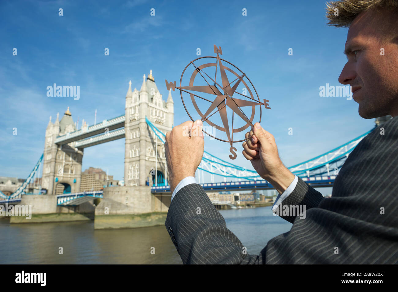 European businessman holding old-fashioned compass rose in front of Tower Bridge, London, UK Stock Photo