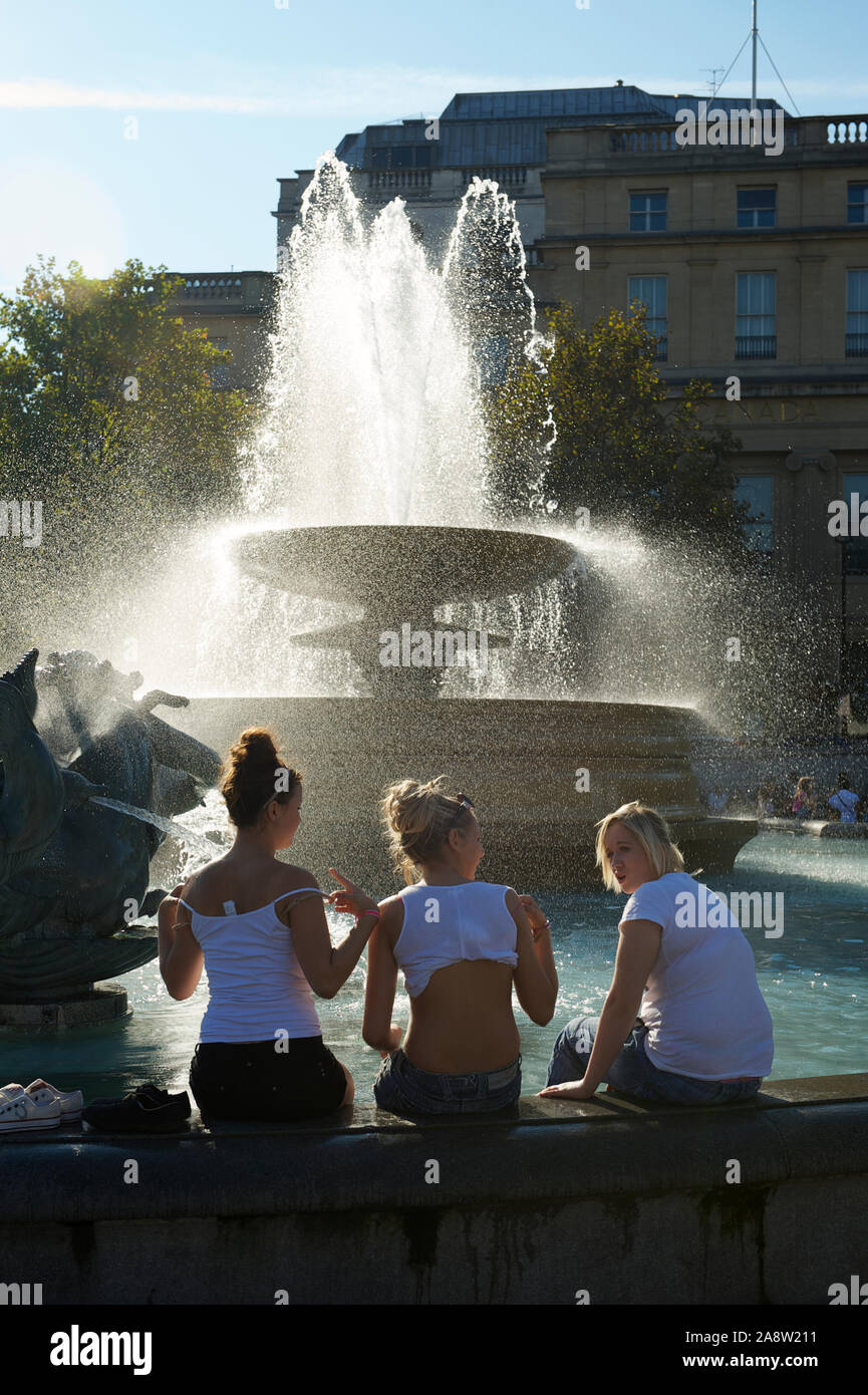 LONDON - SEPTEMBER 2, 2011: Londoners dip their feet in one of the fountains in Trafalgar Square to cool off from an end of summer heatwave. Stock Photo