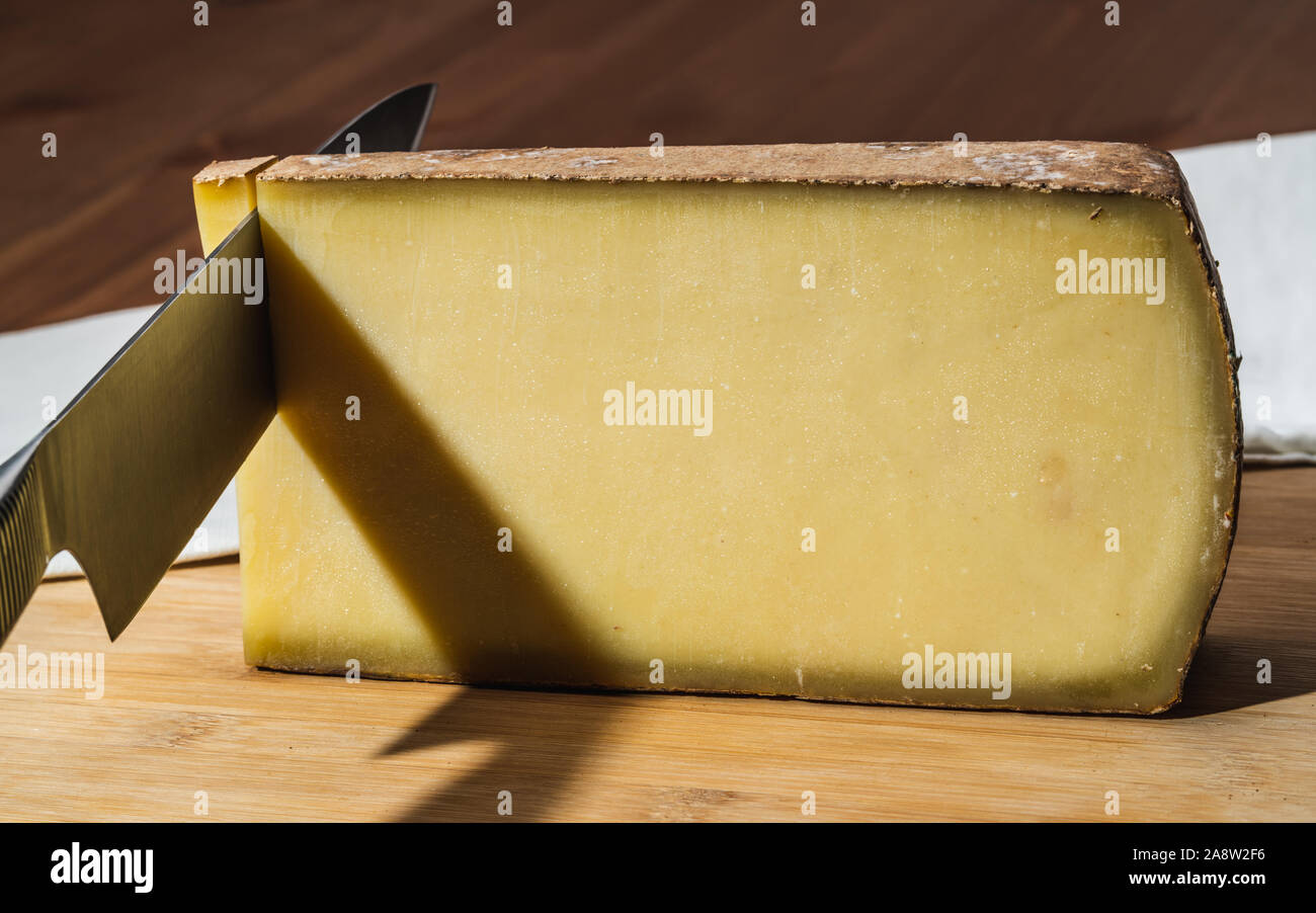 Knife cutting a piece of aged Comte a famous French cheese Stock Photo