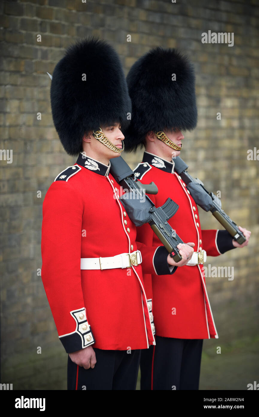 LONDON - MAY 6, 2012: Royal guards stand in traditional red jackets and busby hats, which are made with fur from the Canadian brown bear. Stock Photo