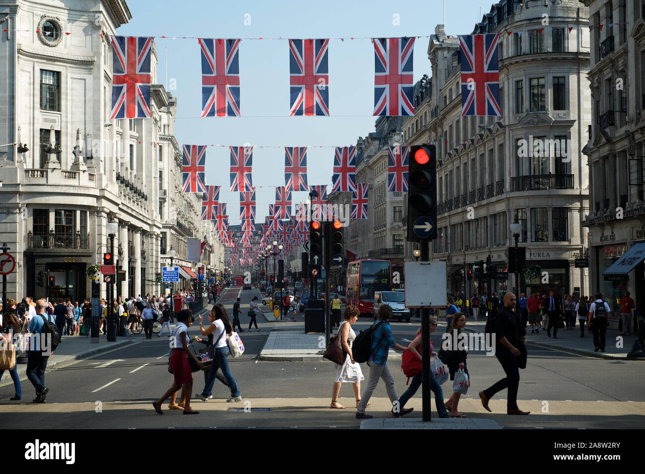 LONDON - MAY 24, 2012: British Union Jack flags decorate a busy intersection full of pedestrians in the Regent Street shopping district. Stock Photo