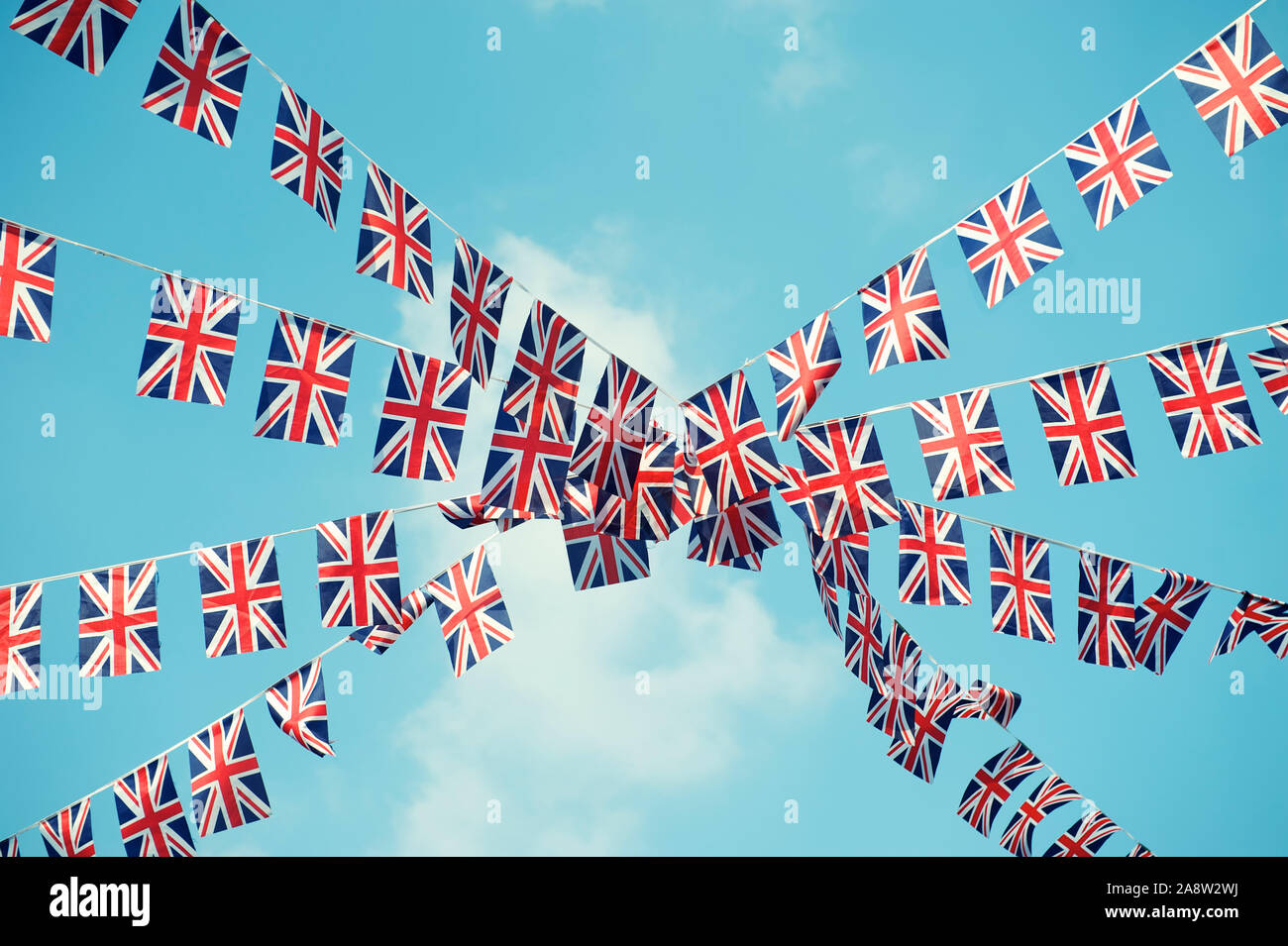 British Union Jack flag bunting strung across soft blue sky Stock Photo