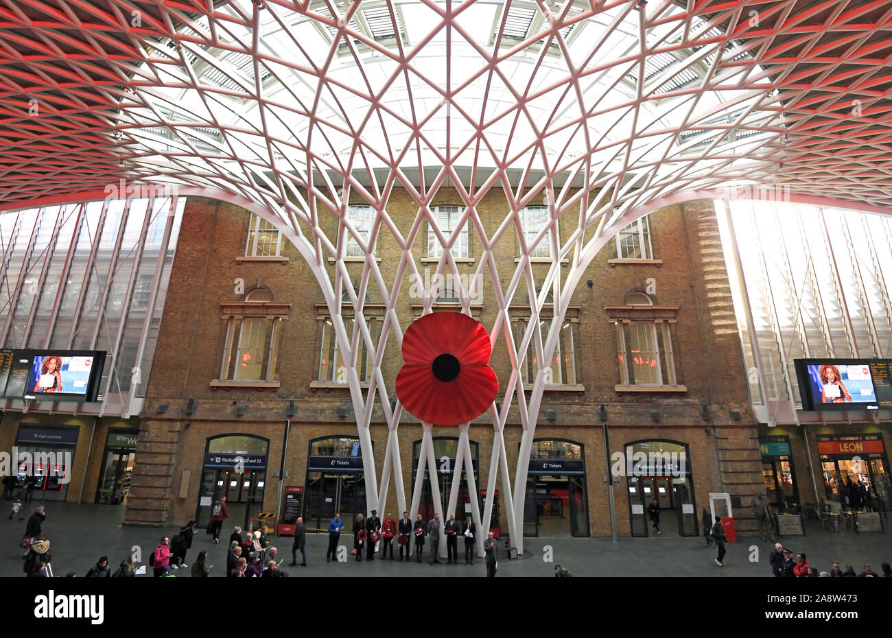 A large model of a poppy on display at King's Cross St. Pancras Station in London, as people observe a silence to mark Armistice Day, the anniversary of the end of the First World War. Stock Photo