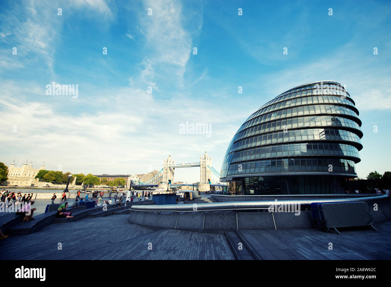 LONDON - OCTOBER 1, 2011: People walk along the Thames path in front of City Hall, the 10-story building designed by architect Sir Norman Foster. Stock Photo