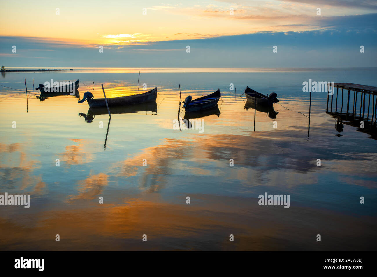 beautiful sunrise over water and silhouette of fishing boat Stock Photo ...