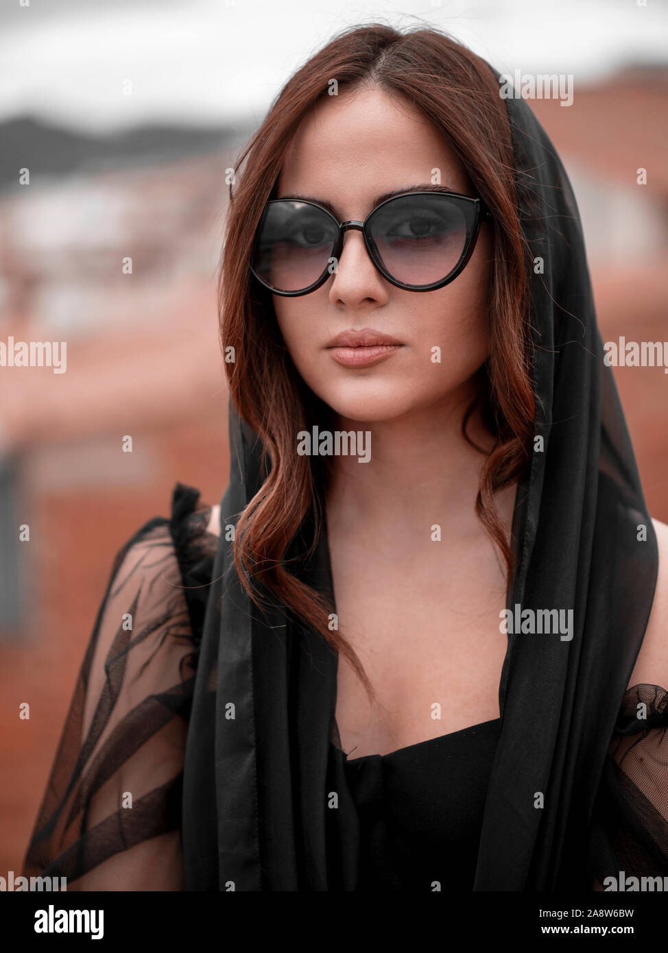 Beautiful young woman wearing sunglasses and elegant black clothing Stock Photo