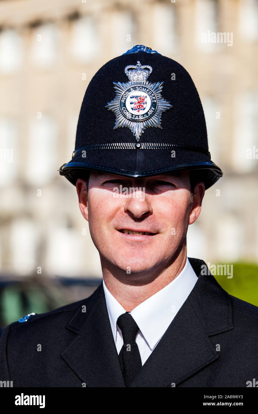 A close up head shot of a British Police Officer, or Bobby, in full dress uniform wearing a traditional custodian helmet Stock Photo