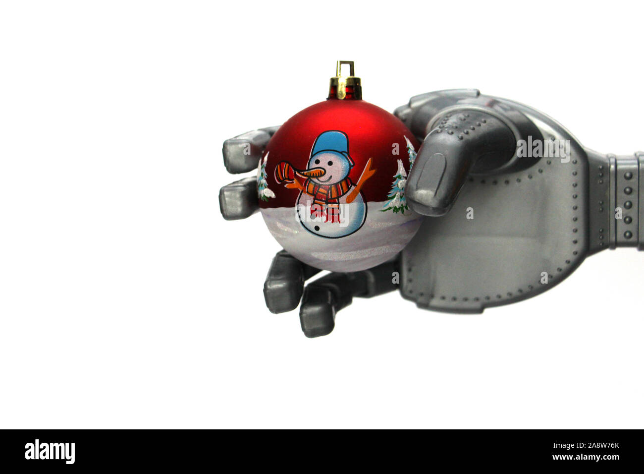 A robot holds a Christmas tree decoration in his hand. Christmas ball with a picture of a snowman. Concept of celebrating Christmas and New Year in th Stock Photo