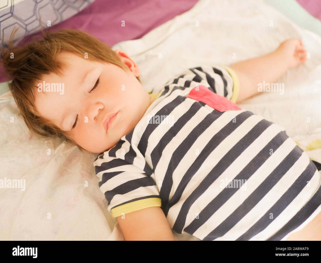 Sleeping baby on parents bed. 0-1 year old baby. Portrait of a newborn in the parents bed. Baby's daytime sleep. Carefree life of children. Good sleep Stock Photo