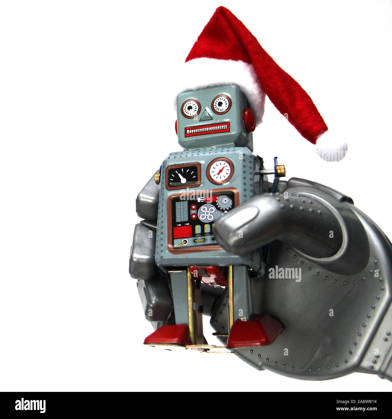 The robot holds a small retro robot in his hand. The robot has a Santa hat.  Christmas and New Year celebration concept in the style of robots. White b  Stock Photo -