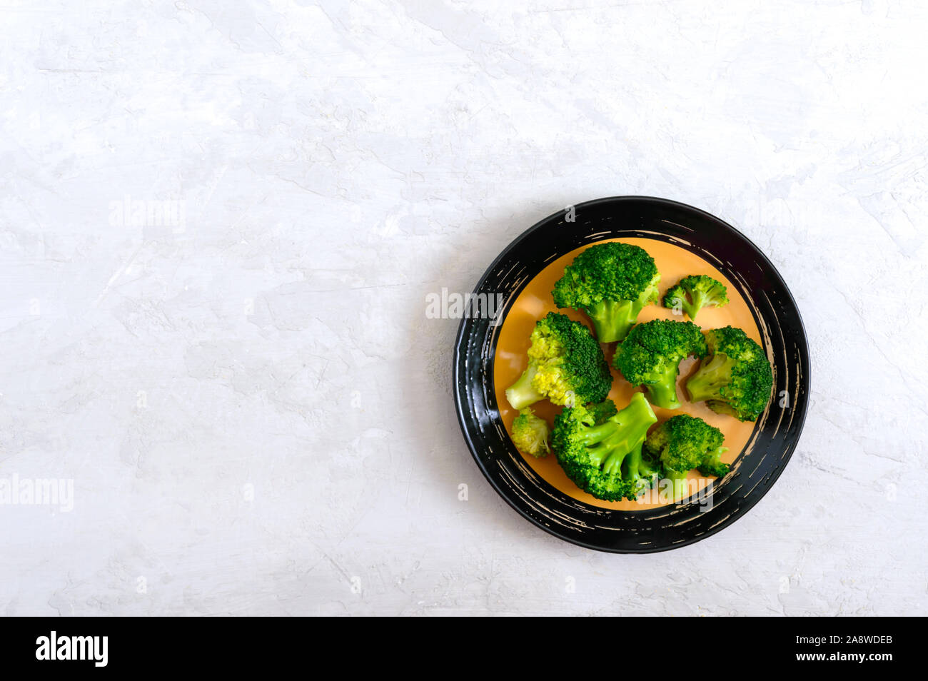 Boiled broccoli on a plate on a light background. Healthy eating concept. Sports diet. Proper