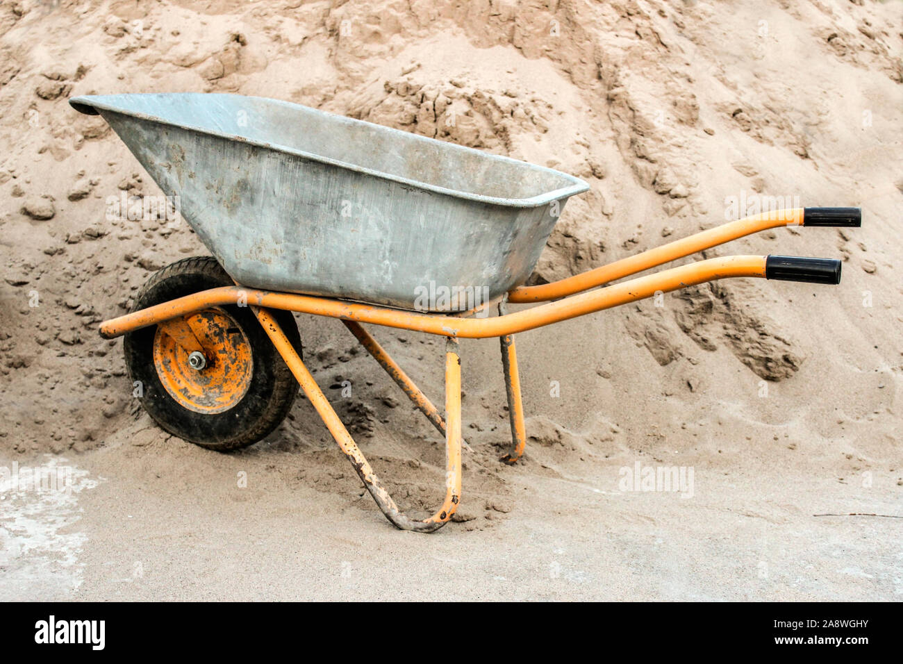 Construction wheelbarrow closeup against a pile of sand Stock Photo