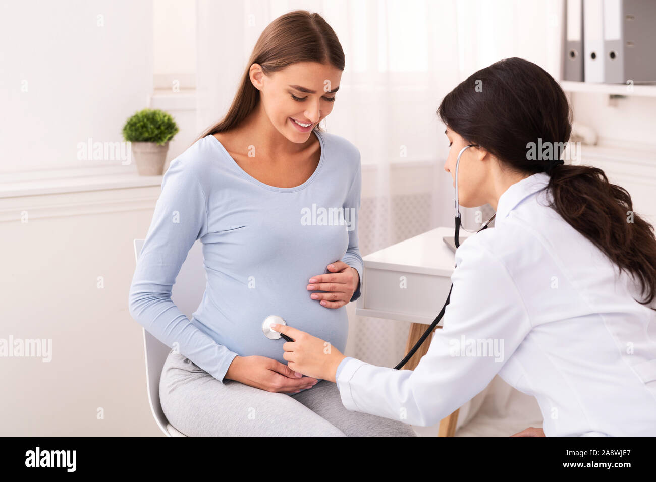 Doctor Examining Pregnant Woman Holding Stethoscope Near Belly In