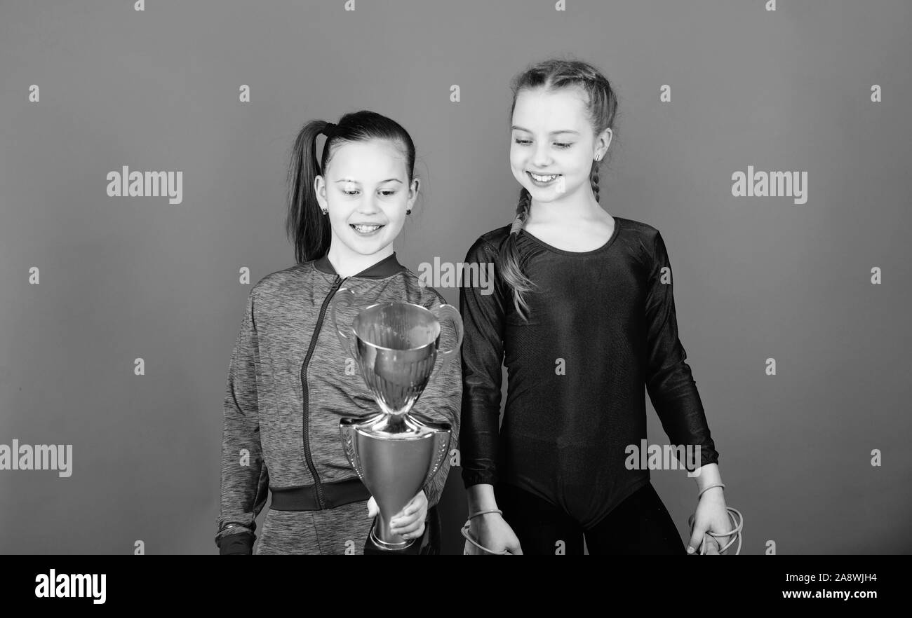 victory of teen girls. Acrobatics and gymnastics. Little girls hold jump rope. Winner in competition. Sport success. Happy children with gold champion cup. hard work brings reward. reward motivation. Stock Photo
