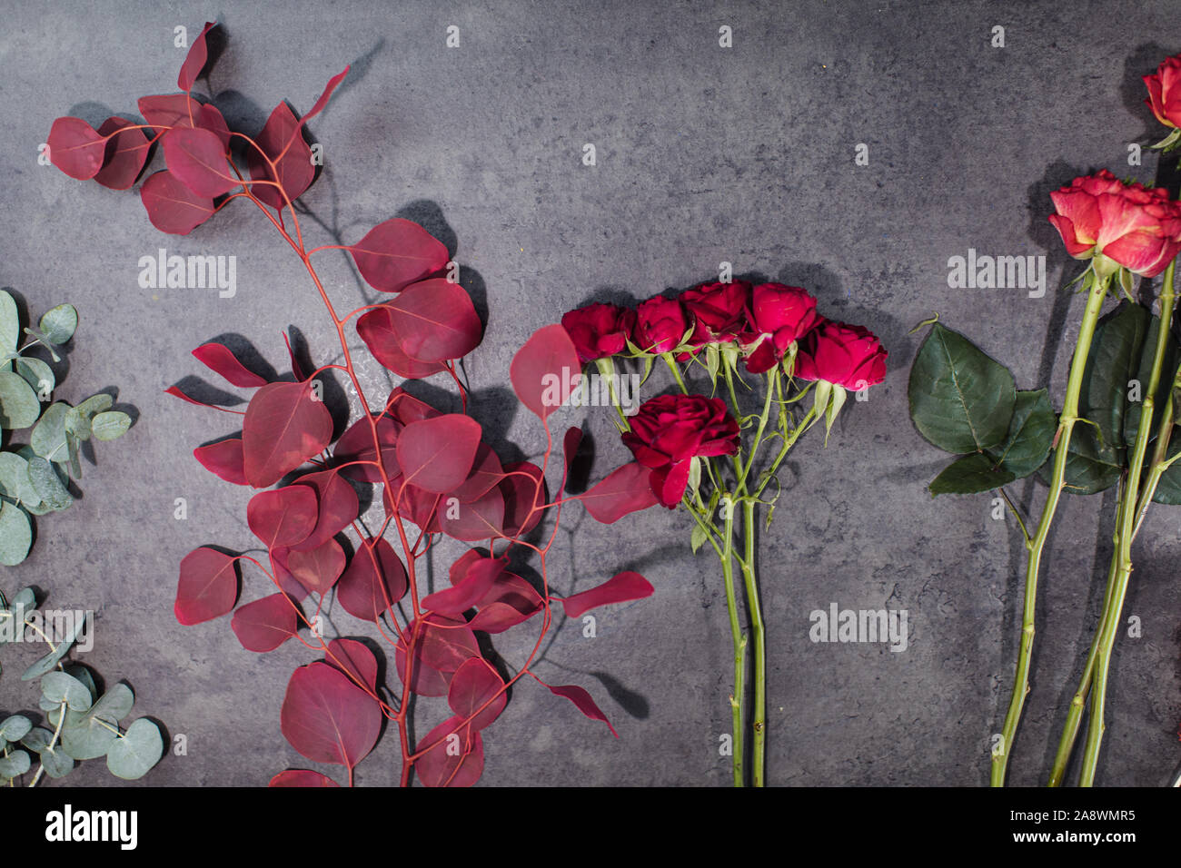 A variety of beautiful flowers lying on a grey table. Flower delivery. The job of a florist Stock Photo