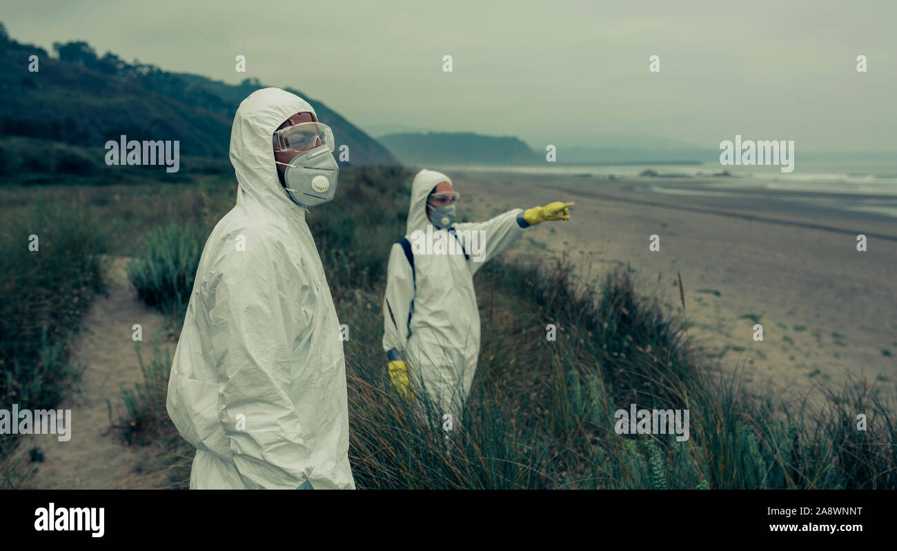 People in bacteriological protective suits watching the sea Stock Photo