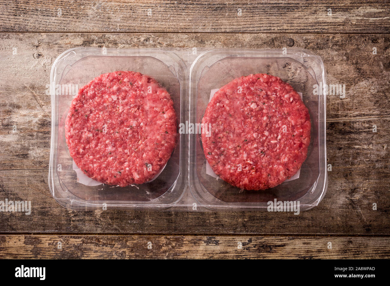 burger meat packaged in plastic on wooden table. Top view Stock Photo