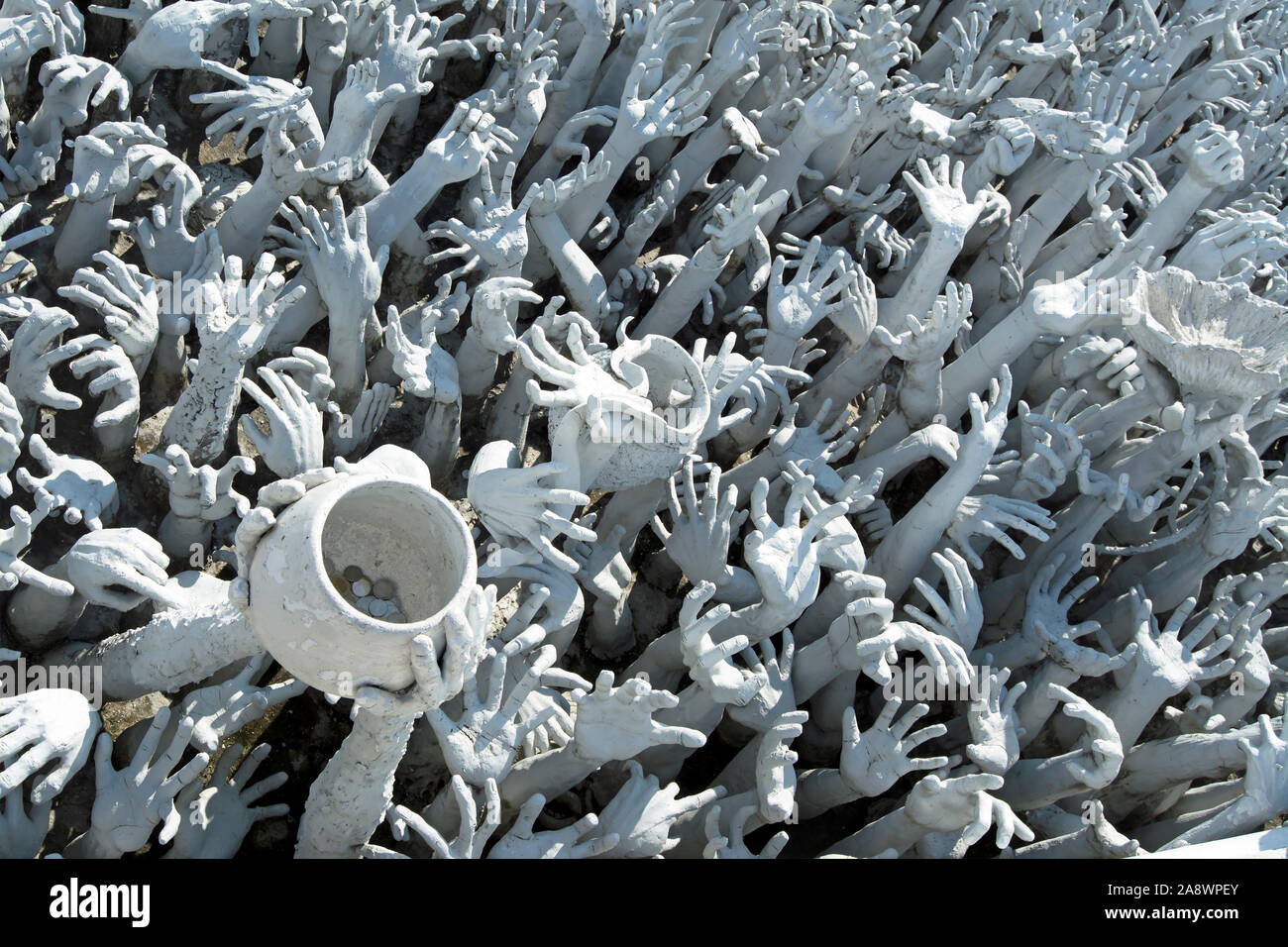 a sculpture at wat rong khun, or the white temple, chiang rai, thailand,  depicting hands reaching from hell and symbolising unrestrained desire Stock Photo