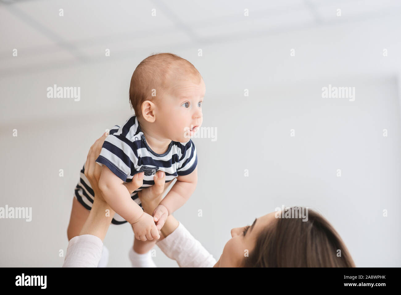 Loving mother lifting adorable newborn baby in air Stock Photo