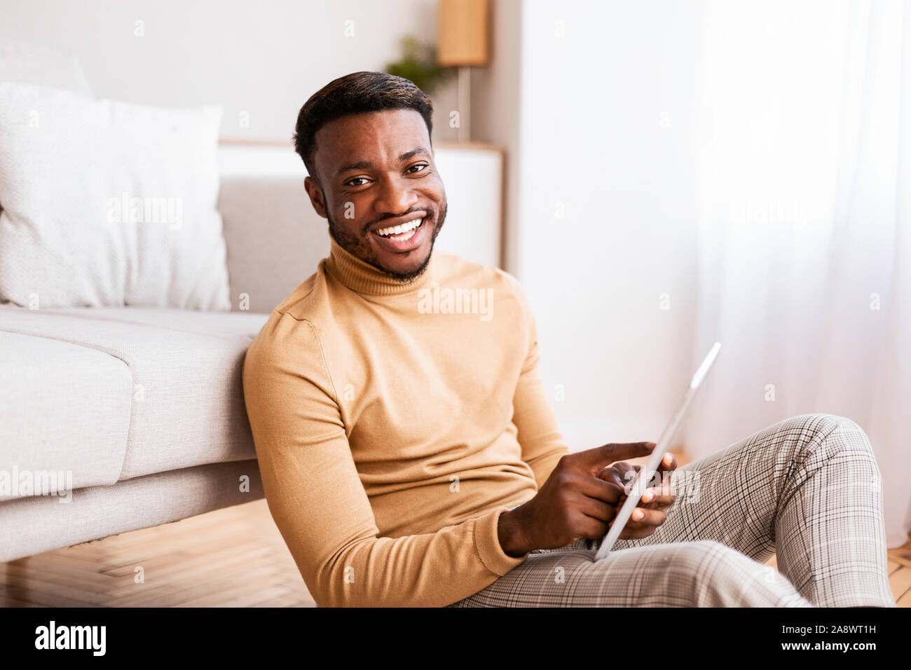 Black Guy Using Tablet Sitting On Floor At Home Stock Photo