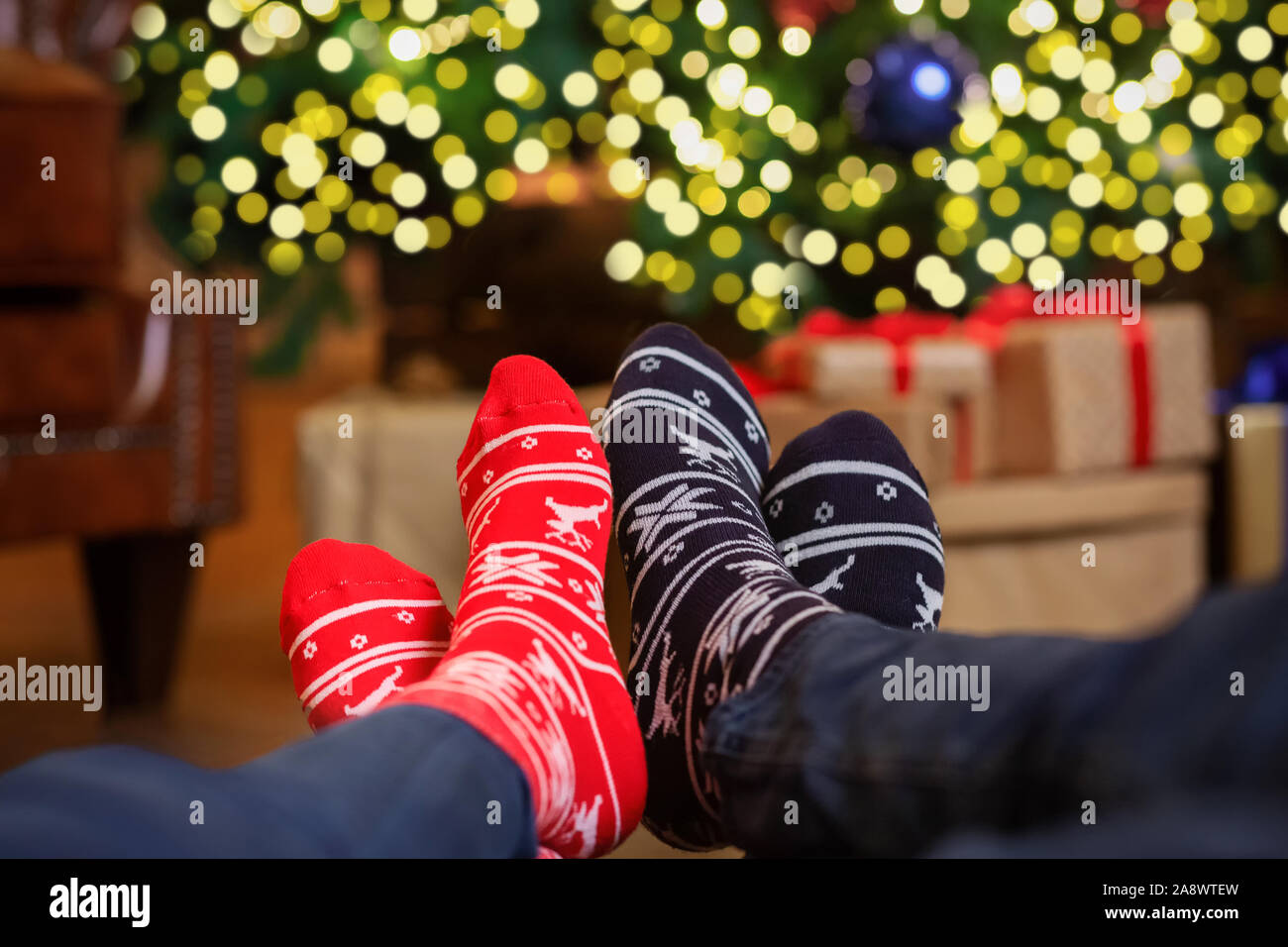 Two pair of feet in colorful ornamented Christmas socks Stock Photo