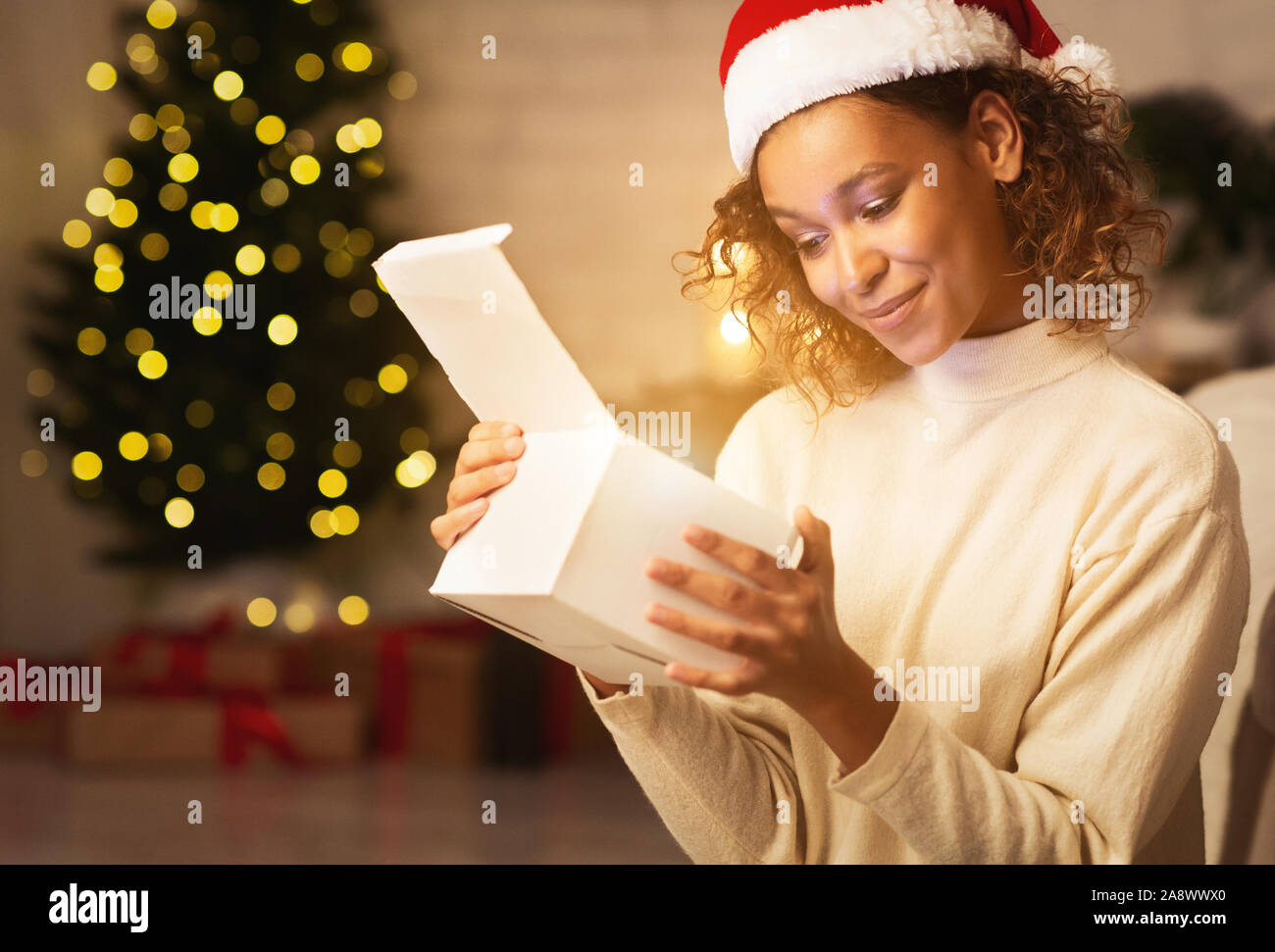 Xmas miracle. Afro lady looking inside present box Stock Photo
