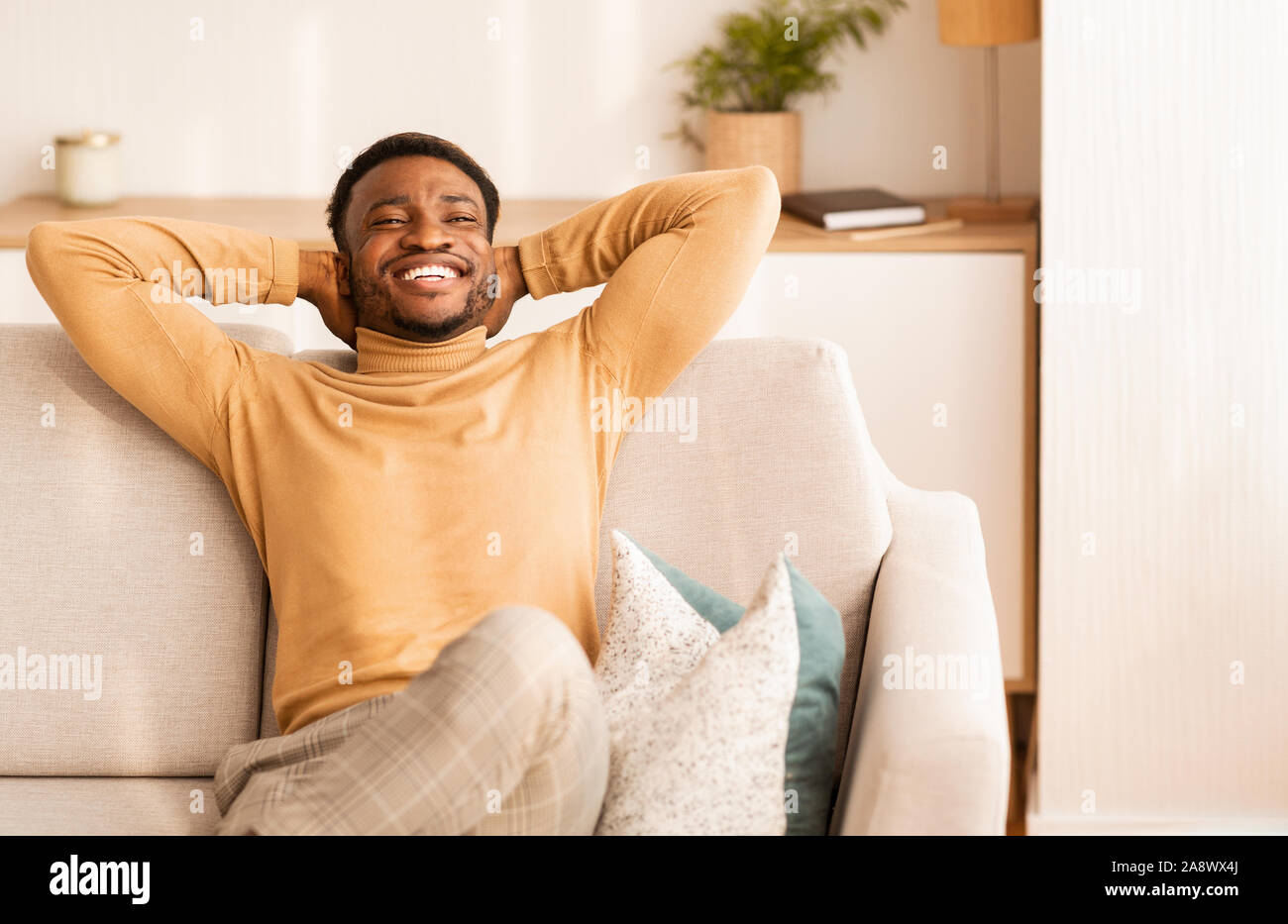Relaxed African American Man Resting Sitting On Couch At Home Stock Photo