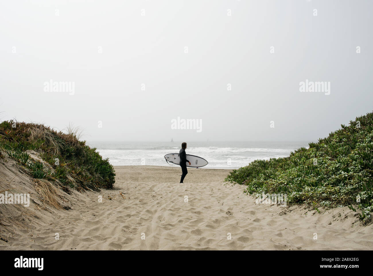 Surfer on the foggy beach of San Francisco, at the end of Taraval St. California, USA. Sep 2019 Stock Photo