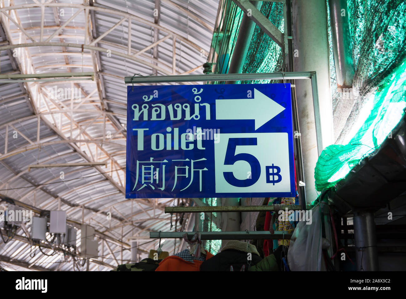in thai, english and chinese, a tri-lingual toilet sign in mae sai, thailand, also showing a charge of five thai baht Stock Photo