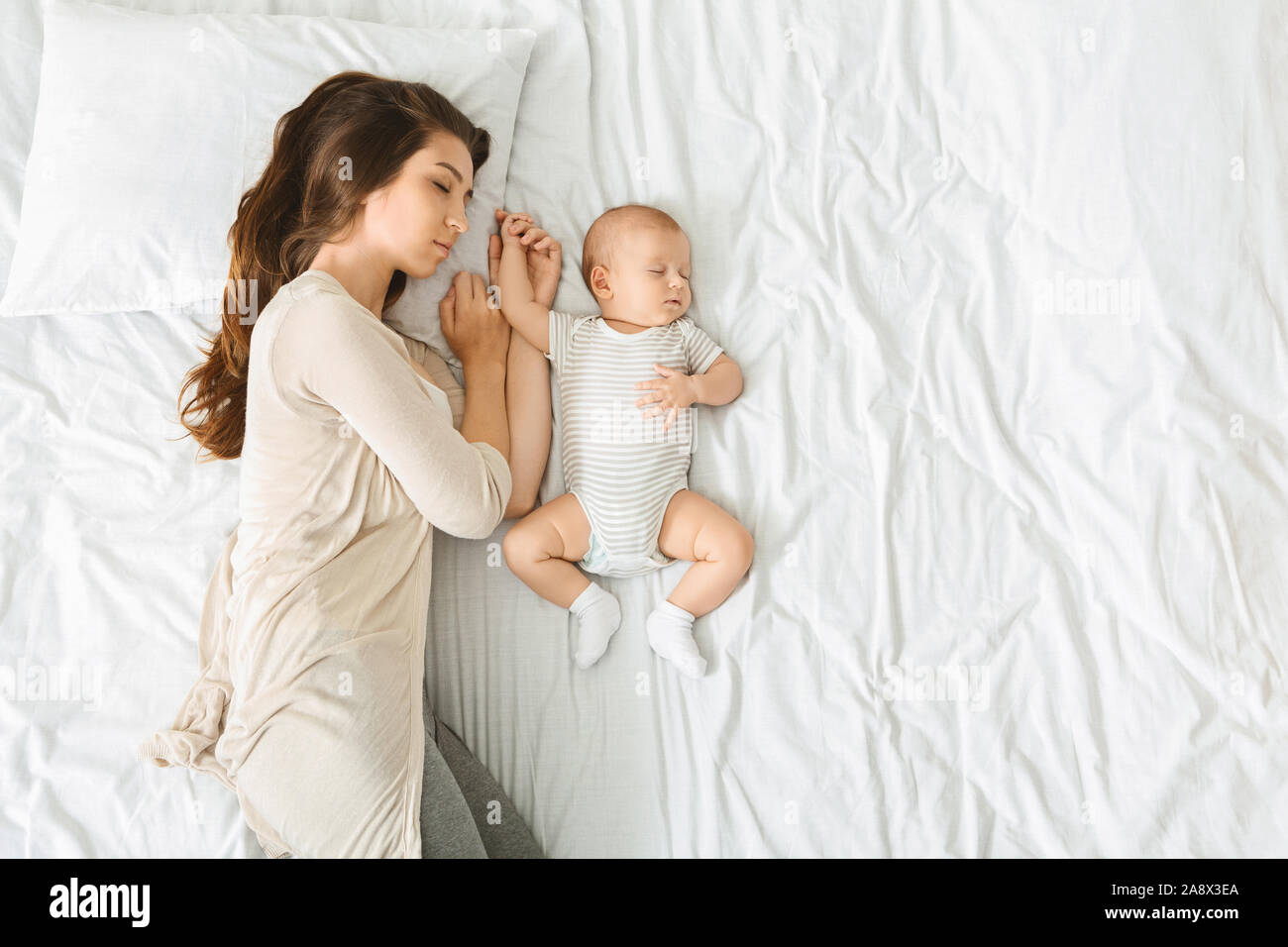 Tired mother sleeping in bed with baby by her side Stock Photo Alamy